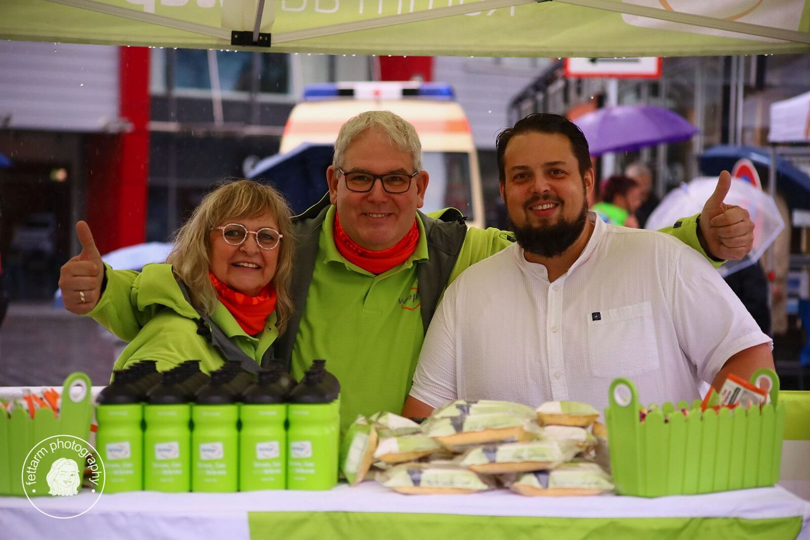 Drei gut gelaunte Helfer am wep-Stand mit Trinkflaschen und Snacks