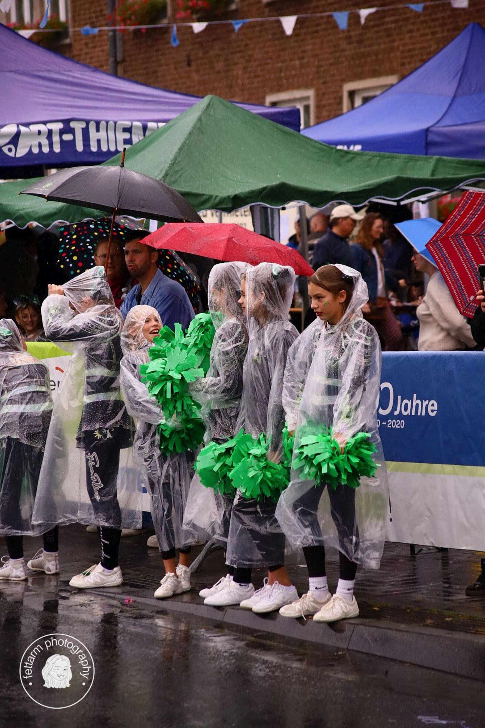 Cheerleader in Regenponchos mit grünen Pompons vor der TuS-Jahn-Bande