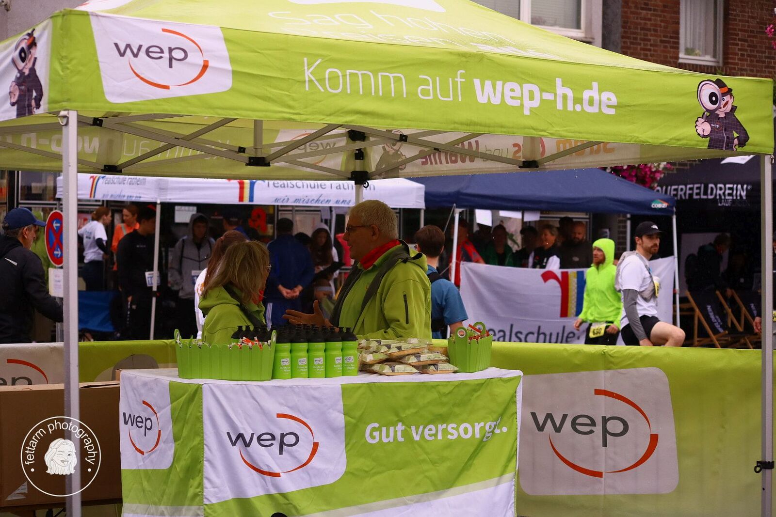 Der wep-Stand mit grünem Pavillon, Trinkflaschen und Verpflegung für die Läufer